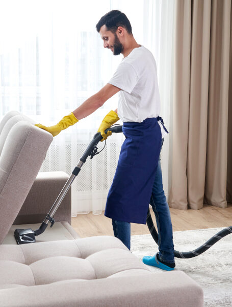Young man Cleaning sofa With Vacuum Cleaner in leaving room At Home Young Man Cleaning sofa With Vacuum Cleaner At Home